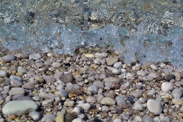 Marine background. The coast of pebbles. Small waves run on the coast