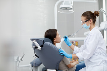 Fototapeta premium Side view portrait of female dentist examining child in clinic, copy space