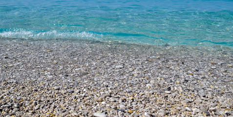 Marine background. The coast of pebbles. Small waves run on the coast
