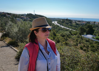 Brunette girl in a hat and sunglasses looks at the road away