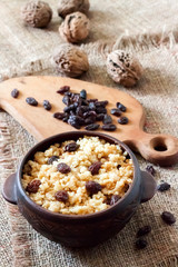 Sweet millet porridge with dark raisins in ceramic rustic bowl
