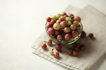 Red and green gooseberries, ripe berries on table in plate.