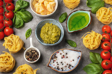 Pasta cooking concept, ingredients and spices on a table with a dish. Popular italian pesto sauce. Vegetarian food. Top view, close-up.
