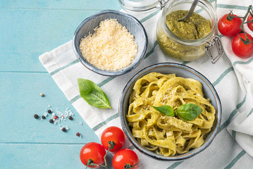 Pasta with pesto sauce, cooking concept, ingredients and spices on a table with a dish. Top view, copy space. Vegetarian food.