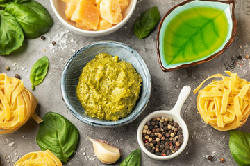 Popular italian pesto sauce. Pasta cooking concept, ingredients and spices on a table with a dish. Vegetarian food. Top view, close-up.