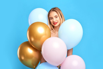 Fototapeta na wymiar smiling romantic blonde girl standing behind many air balloons. positive mood, atmosphere. isolated blue background.