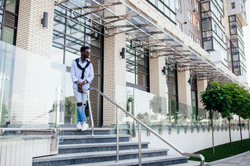 Street style. African american man in  casual suit stay on stairs.