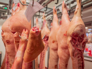 Processed meat carcasses hanging on hooks. Pork ready for processing. Meat workshop of specialized supermarket. Own production