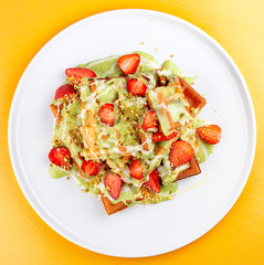 Belgian waffles with pistachio cream topping and strawberries