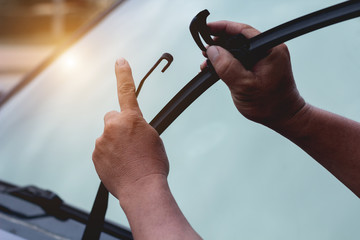 Mechanic replace windshield wipers on car. Replacing wiper blades - obrazy, fototapety, plakaty
