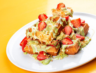 Belgian waffles with pistachio cream topping and strawberries