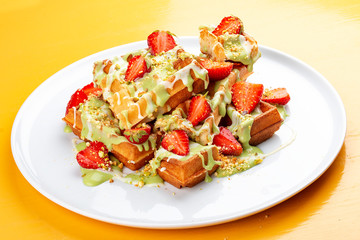 Belgian waffles with pistachio cream topping and strawberries