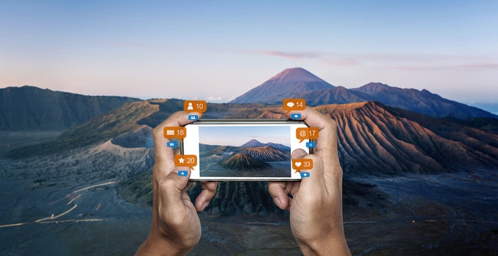 Hand taking photo of Mount Bromo volcanic, famous travel destination in Indonesia with social media notification icon