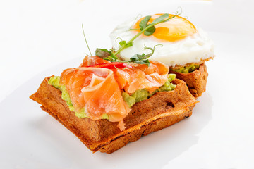 American waffle with salmon and egg, with avocado mousse. Healthy breakfast.