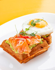 American waffle with salmon and egg, with avocado mousse. Healthy breakfast.