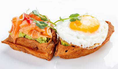 American waffle with salmon and egg, with avocado mousse. Healthy breakfast.