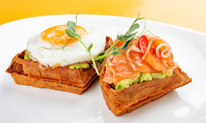 American waffle with salmon and egg, with avocado mousse. Healthy breakfast.