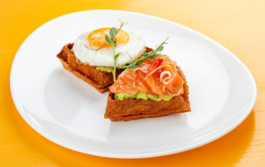 American waffle with salmon and egg, with avocado mousse. Healthy breakfast.