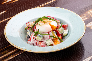 Vegetable salad of radish, cucumber and tomato with poached egg.