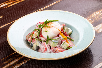 Vegetable salad of radish, cucumber and tomato with poached egg.