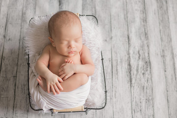 Adorable newborn baby sleeping in cozy room. Cute happy infant baby portrait with sleepy face in...