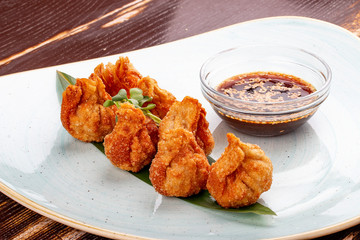 Fried wontons with soy sauce served on a bamboo leaf.