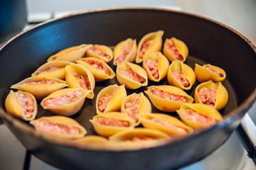 Stuffed conchiglioni in a pan. Fresh stuffing. Close up