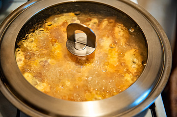 something with cheese to prepare for breakfast in a frying pan, closed lid closeup. top view