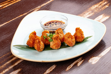 Fried wontons with soy sauce served on a bamboo leaf.