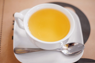 A white Cup of herbal tea on a saucer on a table in a cafe.