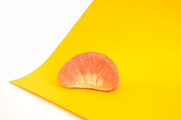 peeled slices of juicy pomelo on yellow and white background