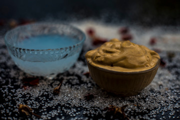 Ubtan/face mask/face pack of Multani mitti or fuller's earth on wooden surface in a glass bowl consisting of Multani mitti and coconut oil for the remedy or treatment of suntan.On the wooden surface.
