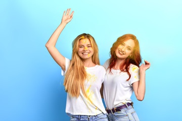 two happy girls celebraiting traditional indian spring holiday.close up photo. isolated blue background, studio shot. lifestyle, free time, spare time