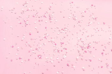 Festive abstract background for the design. Colorful confetti on a pink background. Top view, flat lay composition. Copy space for text.