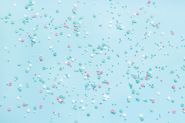 Festive abstract background for the design. Colorful confetti on a blue background. Top view, flat lay composition. Copy space for text.