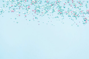 Festive abstract background for the design. Colorful confetti on a blue background. Top view, flat lay composition. Copy space for text.