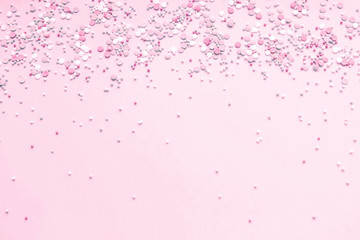 Festive abstract background for the design. Colorful confetti on a pink background. Top view, flat lay composition. Copy space for text.