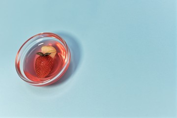 Strawberry glitter jelly with apple and basil in a transparent rosette. On the left, tilted, on a blue background.