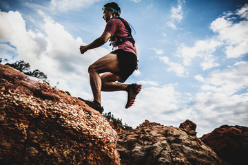 side view of trail runner jumping on the horizon and stone © pixfly
