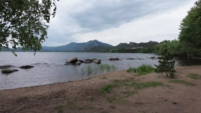 The beach of the lake near the mountains, rocks and trees in Borovoe, Kazakhstan