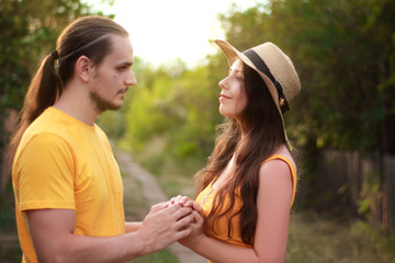A man and a young woman in bright yellow clothes on a village street. A couple in love, summer, hot day, bright colors.