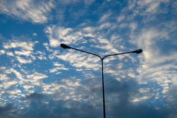 Blue sky background with clouds and silhouette of electric pole