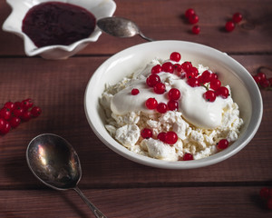 Light breakfast of cottage cheese with sour cream and red currant berries, shot from close range