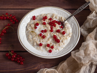 Oatmeal with red currant berries in a white deep bowl