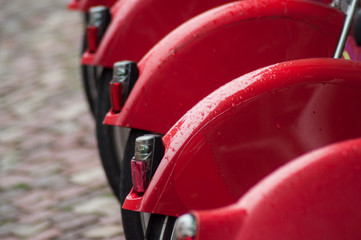 Closeup of rain drops on red city bicycle on cobblelstone background