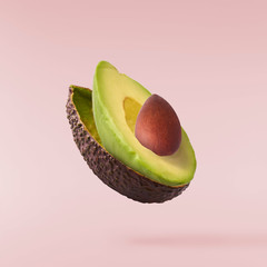 Fresh ripe avocado with leaves falling in the air. - obrazy, fototapety, plakaty