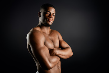 Fototapeta premium confident serious personal trainer with folded arms posing to the camera, isolated black background. confidence concept. copy space