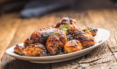 Grilled hicken legs BBQ with spices herbs and sesame on baked paper. Roasted poultry meal on white plate