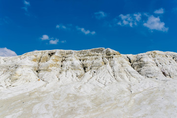 Kaolin hill in abandoned quarry  in Harghita Bai, Romania, blue sky with white clouds background.
