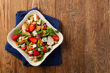Delicious salad with fried chicken, blue cheese, strawberries and walnuts. Top view.